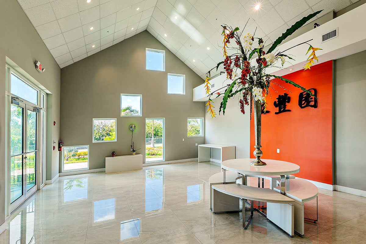 A tall flower vase in the center of the main lobby with an orange accent wall